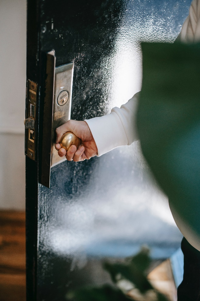 a person turning door handle while entering house
