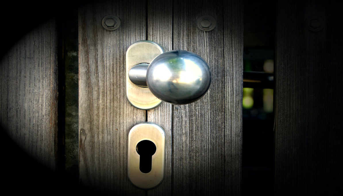 A silver door knob is installed into a textured door.