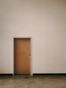 A wooden door is installed on a plain white wall.
